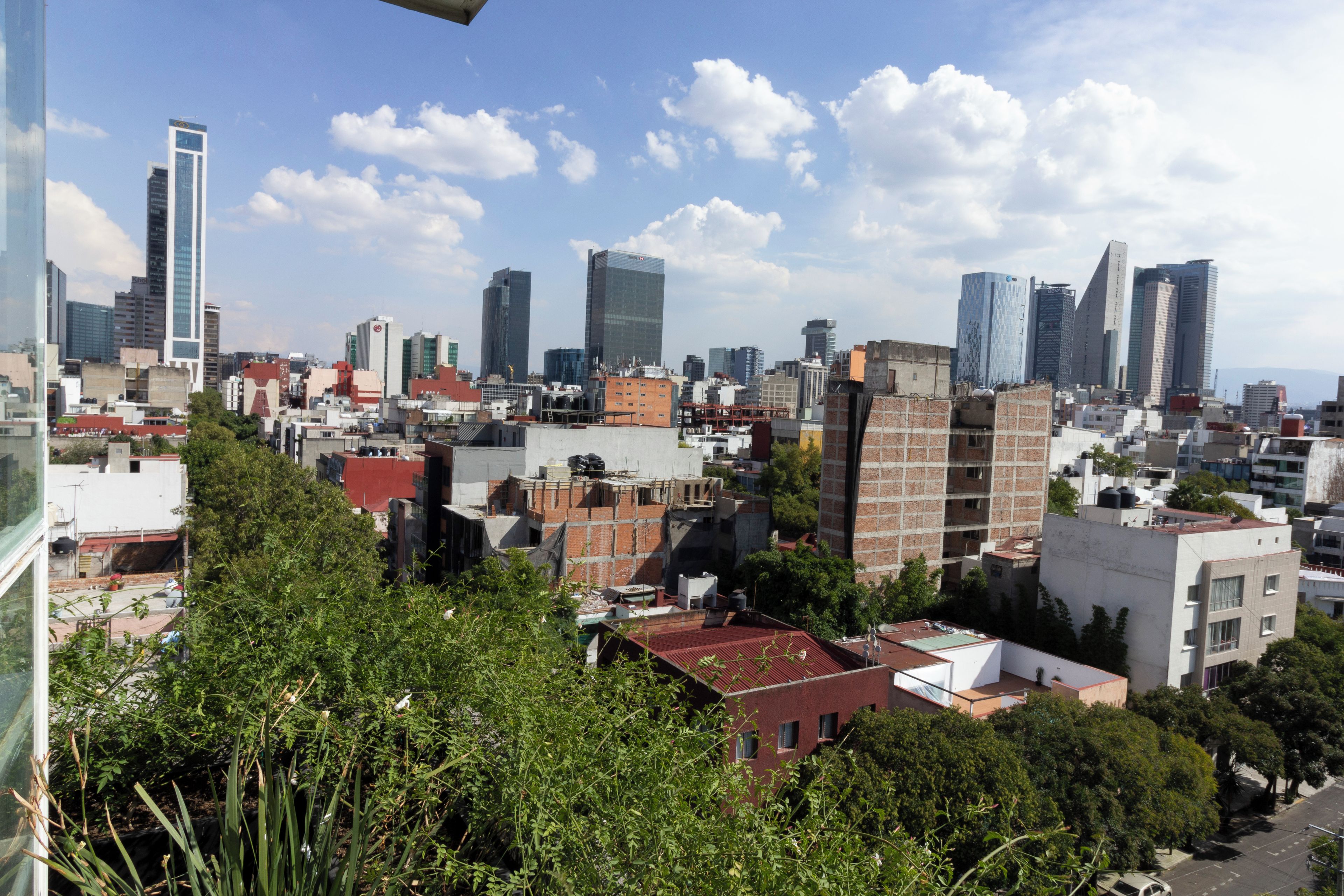 Eine Stadtsicht mit einer Mischung aus modernen und älteren Gebäuden, darunter ein markanter Wolkenkratzer.