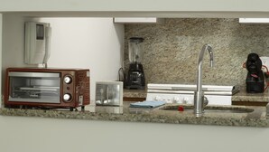 A kitchen with a toaster oven, a blender, a coffee maker, and a stainless steel sink. - Balsas By Homirent (Mexico City)