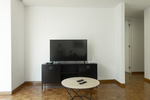A modern living room with a flat-screen TV on a black entertainment unit, a round coffee table, and a wooden parquet floor. - Balsas By Homirent (Mexico City)