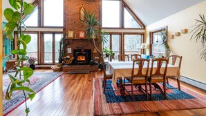 Una habitación espaciosa con techo alto, chimenea de ladrillo y ventanas grandes.