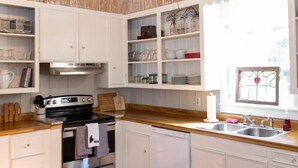 A kitchen with wooden cabinets, a stainless steel stove, and a chandelier. - 1880's Cozy Cottage, close to Historical Downtown. Sleeps up to 6
3B3B-pets OK (Natchez)