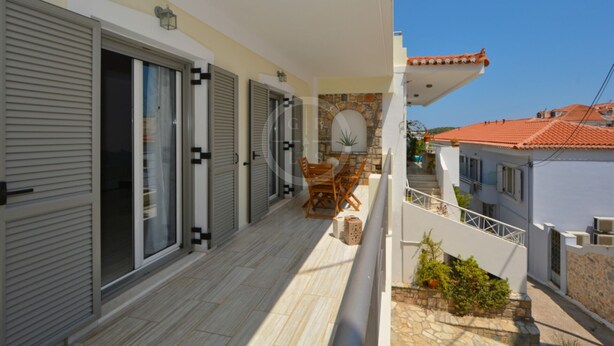 A balcony with a table and chairs, a stone wall, and a view of neighboring buildings. - A contemporary inn situated in the center of Ermioni (Ermioni)
