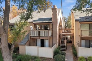Residential building with a covered patio and balcony overlooking a garden.