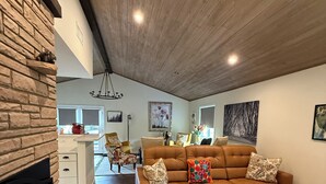 Ein geräumiges Wohnzimmer mit einer braunen Ledersofa, einem Kamin und einem gemusterten Teppich.