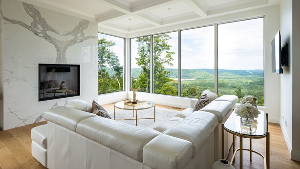 Een moderne woonkamer met een grote hoekbank, een open haard en een groot raam met een prachtig uitzicht.