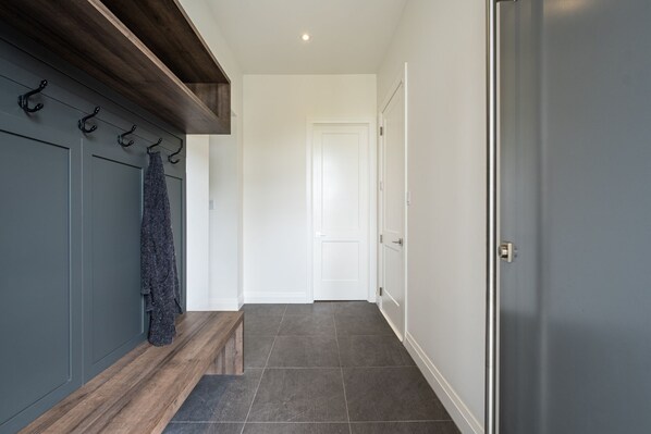 A hallway with a wooden bench, a coat rack, and a door at the end. - Villa Summit | Movie Theater & Game Room | Spectacular Views | Hot Tub, Sauna & Firepit (La Conception)