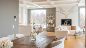 Een moderne woonkamer met een houten eettafel, witte banken en een open haard.
