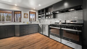 Una cocina moderna con armarios oscuros, electrodomésticos de acero inoxidable y piso de madera.