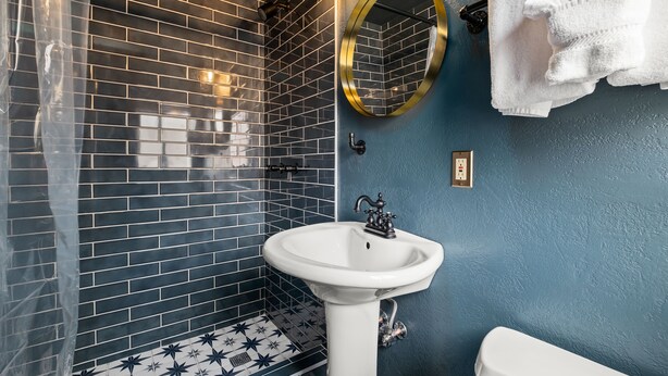 A bathroom with a white sink, a mirror, and a blue wall. - Newly renovated boutique property in the heart of Big Bear Lake! (Big Bear Lake)
