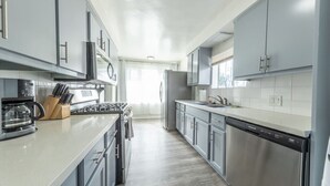 Une cuisine moderne dotée d’appareils électroménagers en acier inoxydable, de meubles de rangement gris et d’un îlot central.