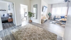 Un salon spacieux avec un grand tapis, un téléviseur et un canapé.