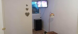 Una habitación con televisión montada en la pared, un altavoz negro, una lámpara y adornos en la pared.