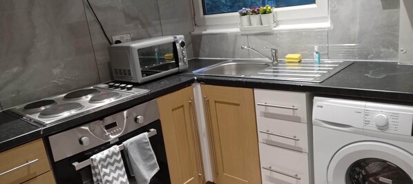 Una cocina compacta equipada con microondas, estufa, lavaplatos y lavadora.