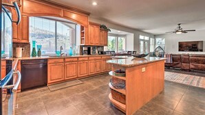 A spacious kitchen with wooden cabinets, a large island, and a dining area with a sofa and TV.