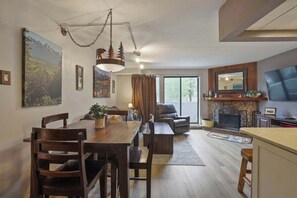 Un vaste espace de vie comprenant une table à manger, des chaises, une cheminée et une grande fenêtre.