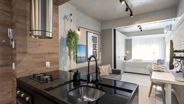A modern kitchen with a stainless steel range hood, a black countertop sink, and a dining area with a white table and chairs. - 3 Minutes From Copacabana Beach Df115 (Rio de Janeiro)