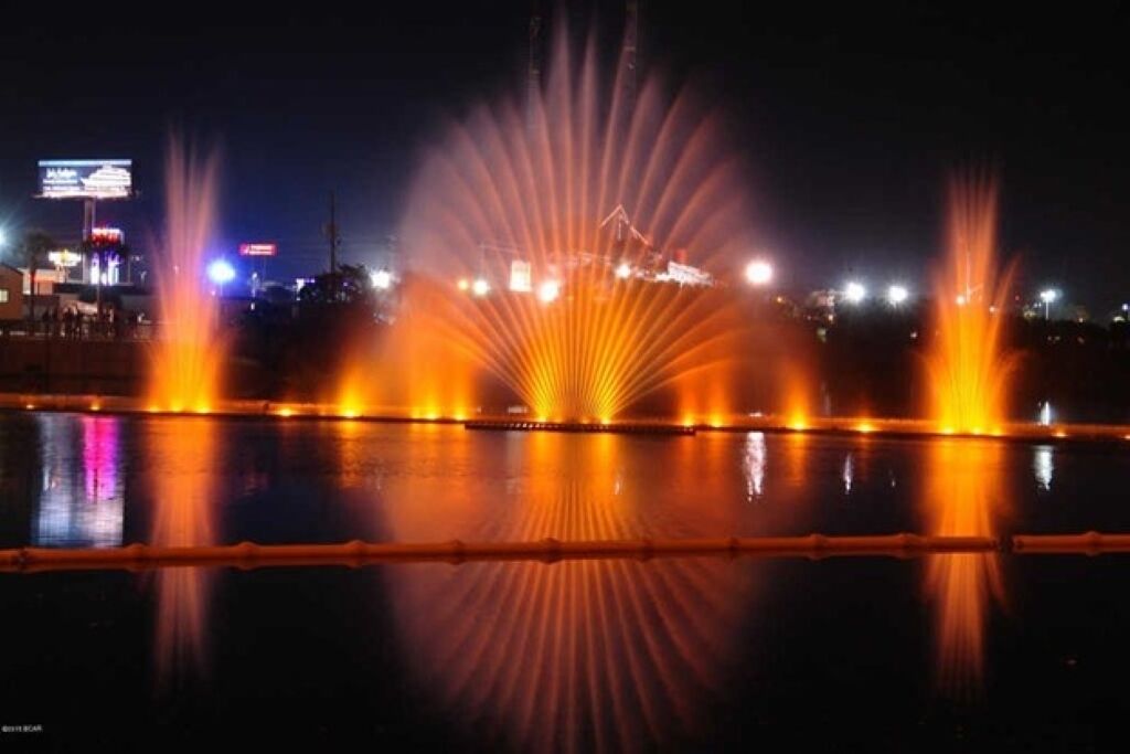 A nighttime view of a water fountain display with lights reflecting on the water's surface.