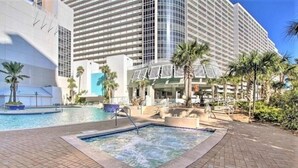 A hotel with a large pool area, palm trees, and a modern building with a glass facade. - Sky Rise Luxurius Beach Beauty (Panama City Beach)