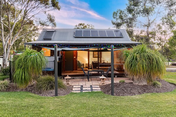 A modern house with a solar panel roof, outdoor seating, and a well-maintained garden. - Goolwa River Retreat (Torrumbarry)