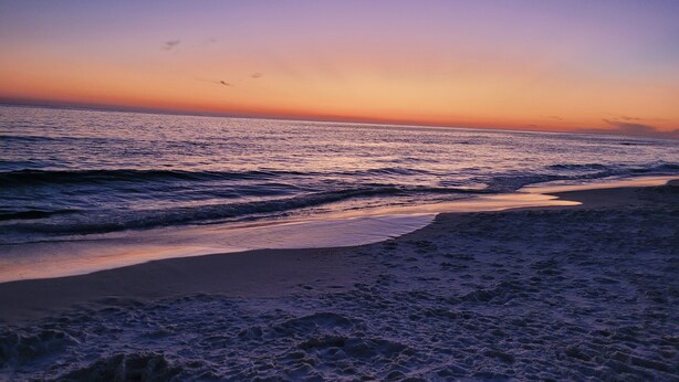 Ein Strand bei Sonnenuntergang, mit Wellen.