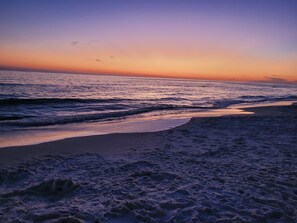 Ein Strand bei Sonnenuntergang, mit Wellen.