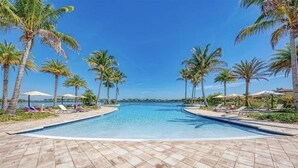 Une piscine bordée de palmiers et dotée de chaises longues.