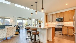 Una cocina moderna con armarios de madera, electrodomésticos de acero inoxidable y una isla grande con taburetes de bar.