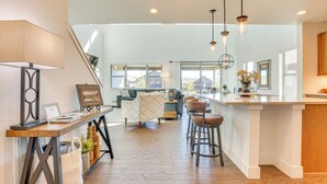 Una cocina amplia con una isla de madera, taburetes de bar e iluminación colgante.