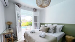 A bedroom with a bed, a desk, a chair, and a view of the outdoors. - Villa · St-François · Golf view & private pool (Saint-François)