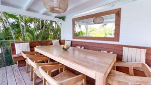 A wooden dining table with benches, a woven ceiling light, and a view of lush greenery outside. - Villa · St-François · Golf view & private pool (Saint-François)
