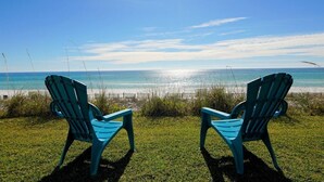 Deux chaises placées face à une plage, sous un ciel dégagé.