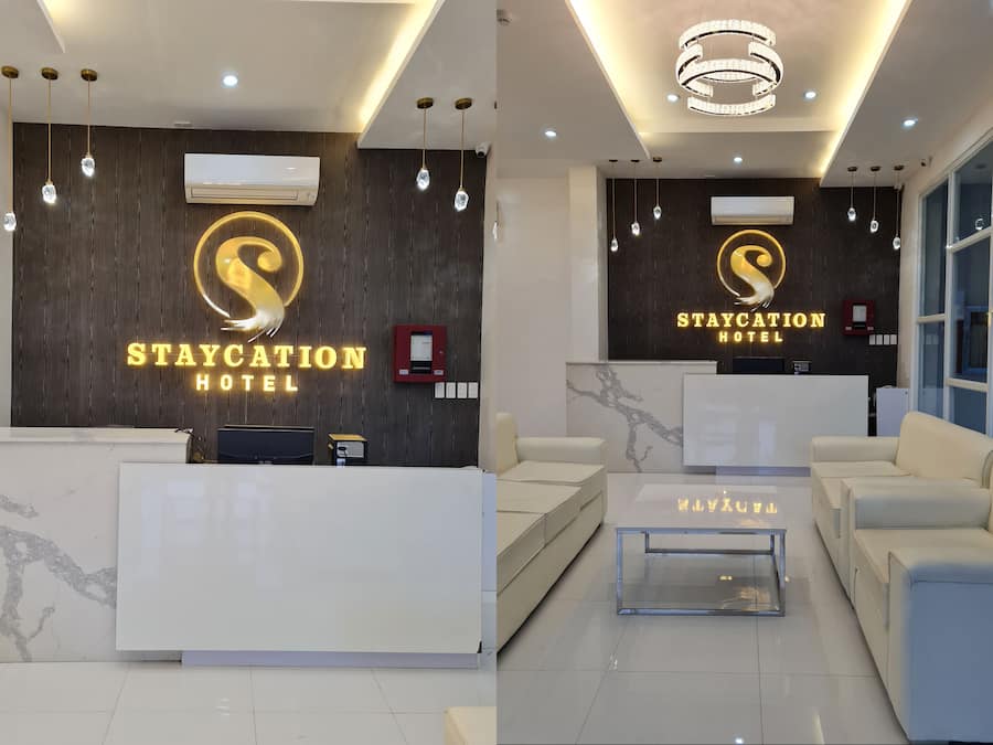 A reception area with a reception desk, sofas, a glass coffee table, and a chandelier.
