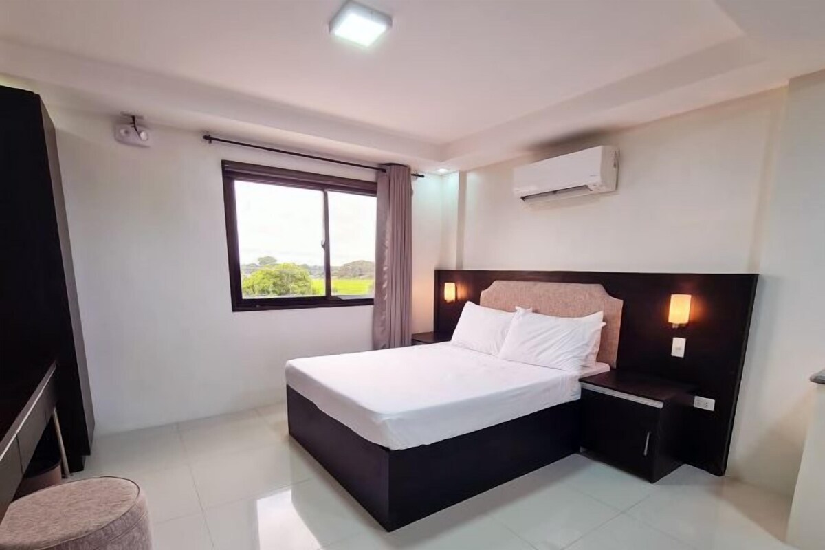 Una habitación de hotel moderna con una cama grande, una mesita de noche y un equipo de aire acondicionado en la pared.