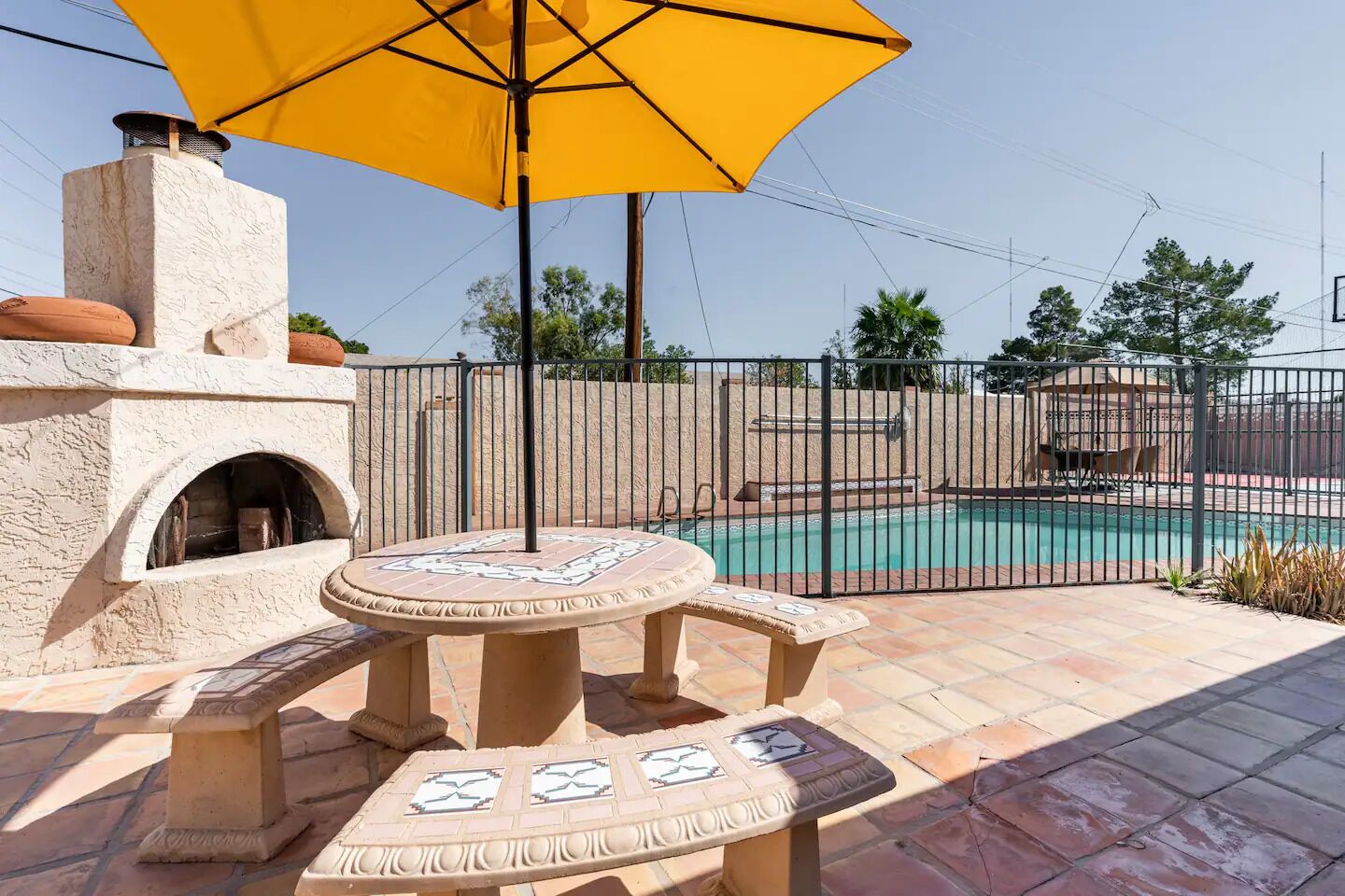 Ein Patio-Bereich mit Pool, Grill und Tisch mit Stühlen.