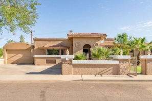 A two-story house with a garage, a front entrance with a gate, and a small patio area with plants. - Spacious home! Heated pool, sundeck, and sports court (Phoenix)