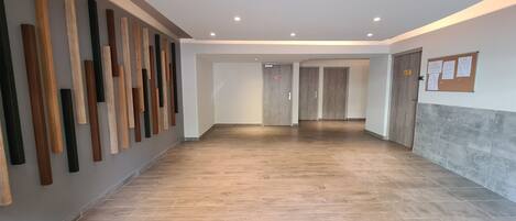 A hallway with wooden planks on the wall, a tiled floor, and doors leading to other rooms.
