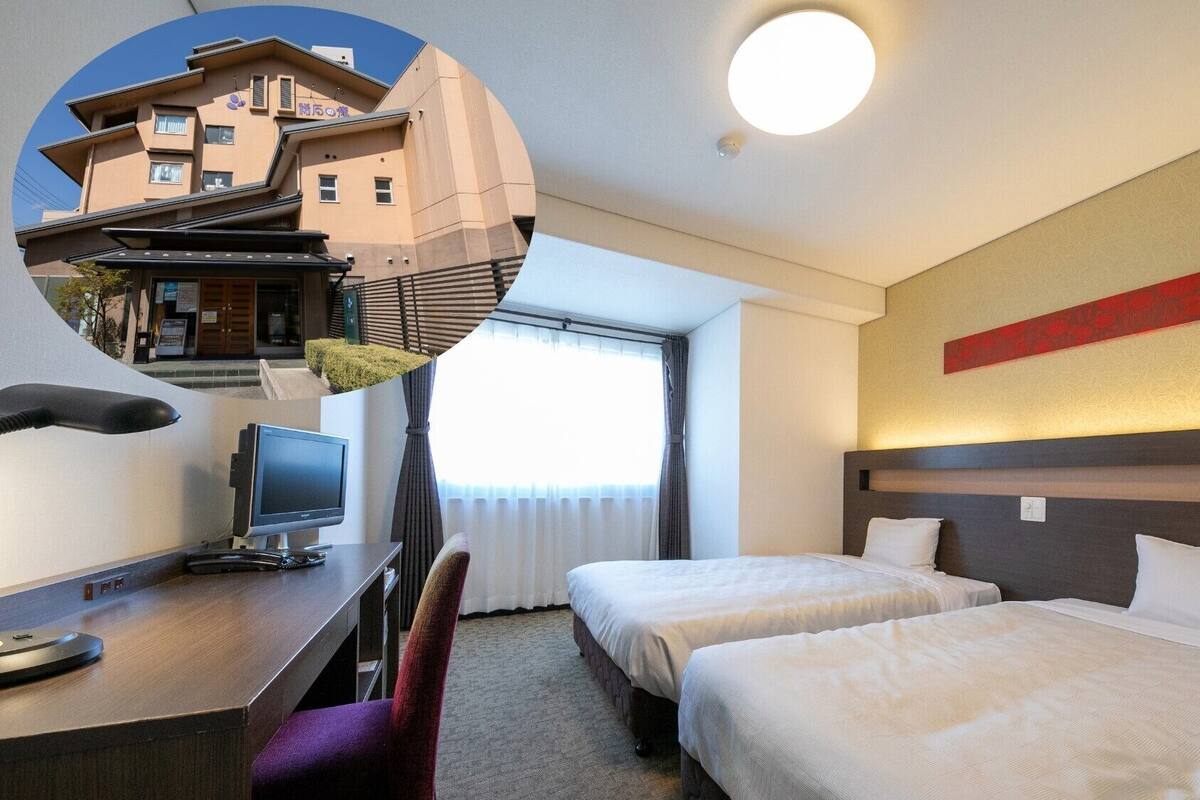 Une chambre d’hôtel avec deux lits, un bureau avec un ordinateur, une télévision et une chaise.