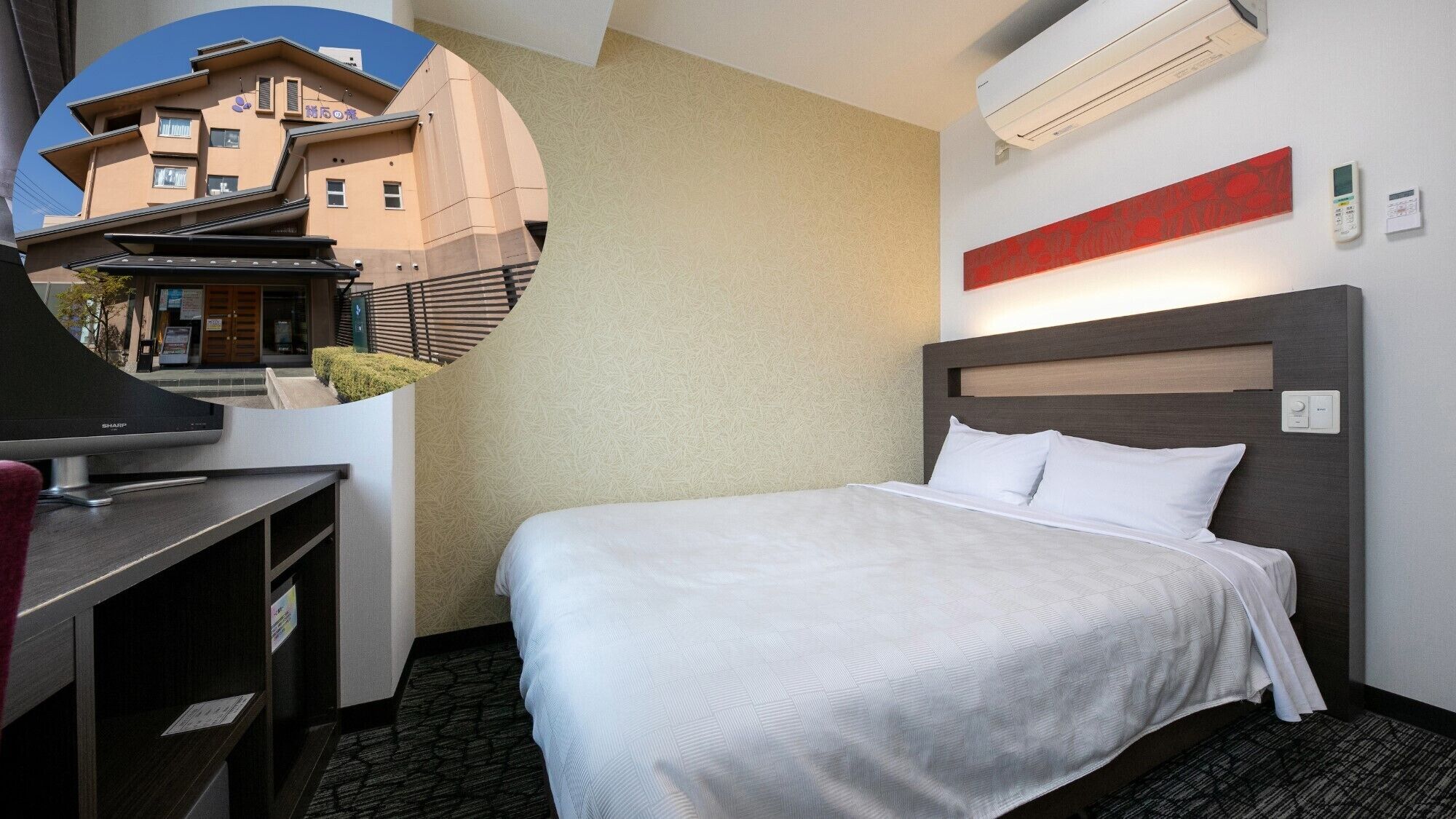 Une chambre d’hôtel équipée d’un lit, d’un bureau, d’une chaise, d’un climatiseur et d’un élément de décoration murale rouge.