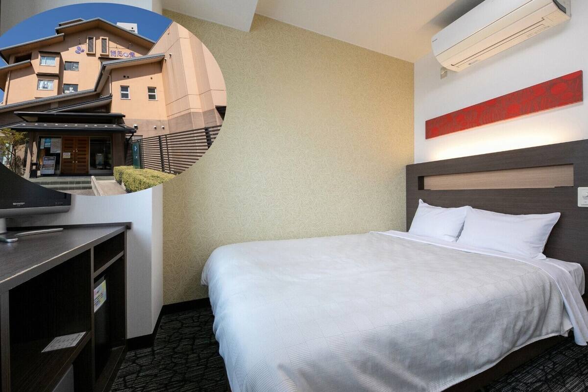 Une chambre d’hôtel équipée d’un lit, d’un bureau, d’une chaise, d’un climatiseur et d’un élément de décoration murale rouge.