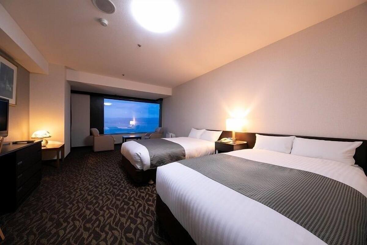 Une chambre d’hôtel avec deux lits, une télévision, un bureau et une chaise.