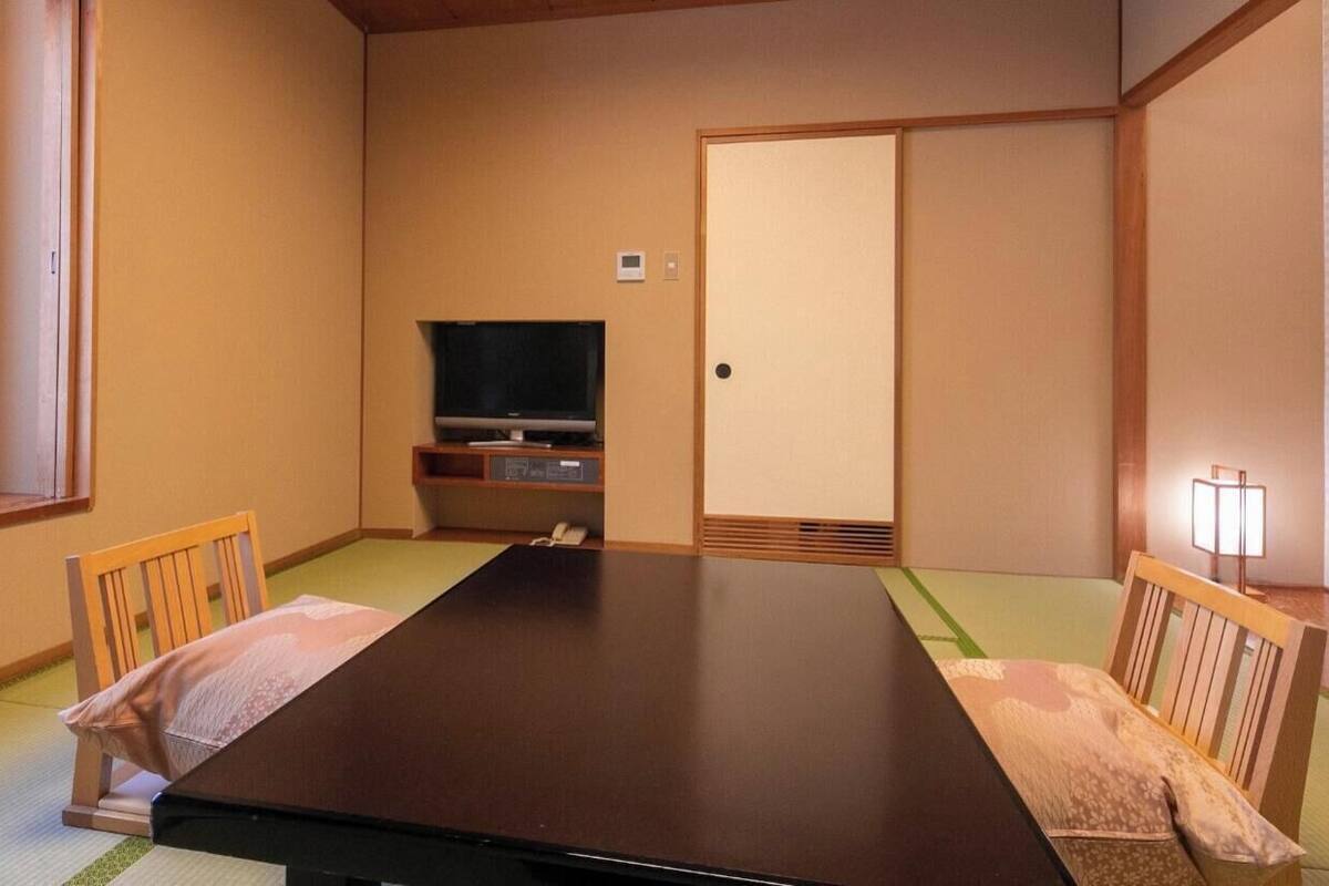 Une pièce de style japonais traditionnel, avec un sol recouvert de tatamis, une table basse et un téléviseur.
