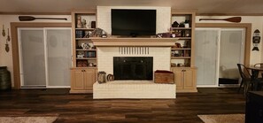 Ein Wohnzimmer mit Kamin, Holzsärchen und Fernseher.