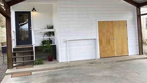 Eine Garage mit Überdachung und Holztür, ein kleiner Vorbereich mit Stufen und ein Blumentopf.