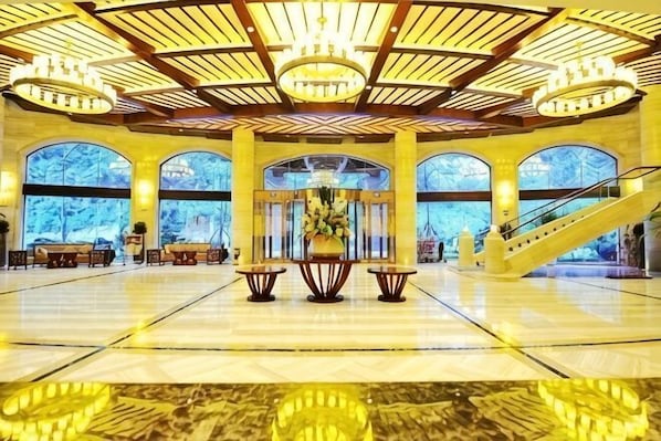 A spacious lobby with a high ceiling, large windows, and a central staircase.