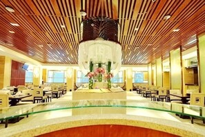 Un hall dâhĂŽtel dotĂ© dâune table centrale en verre, dâun plafond en bois et de plusieurs espaces amĂ©nagĂ©s pour sâasseoir.