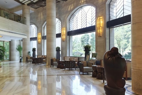 A spacious lobby with high ceilings, large windows, and a central seating area. - Bosai Hotel (Chongqing)