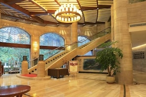 A spacious lobby with a grand staircase, large windows, and a chandelier. - Bosai Hotel (Chongqing)