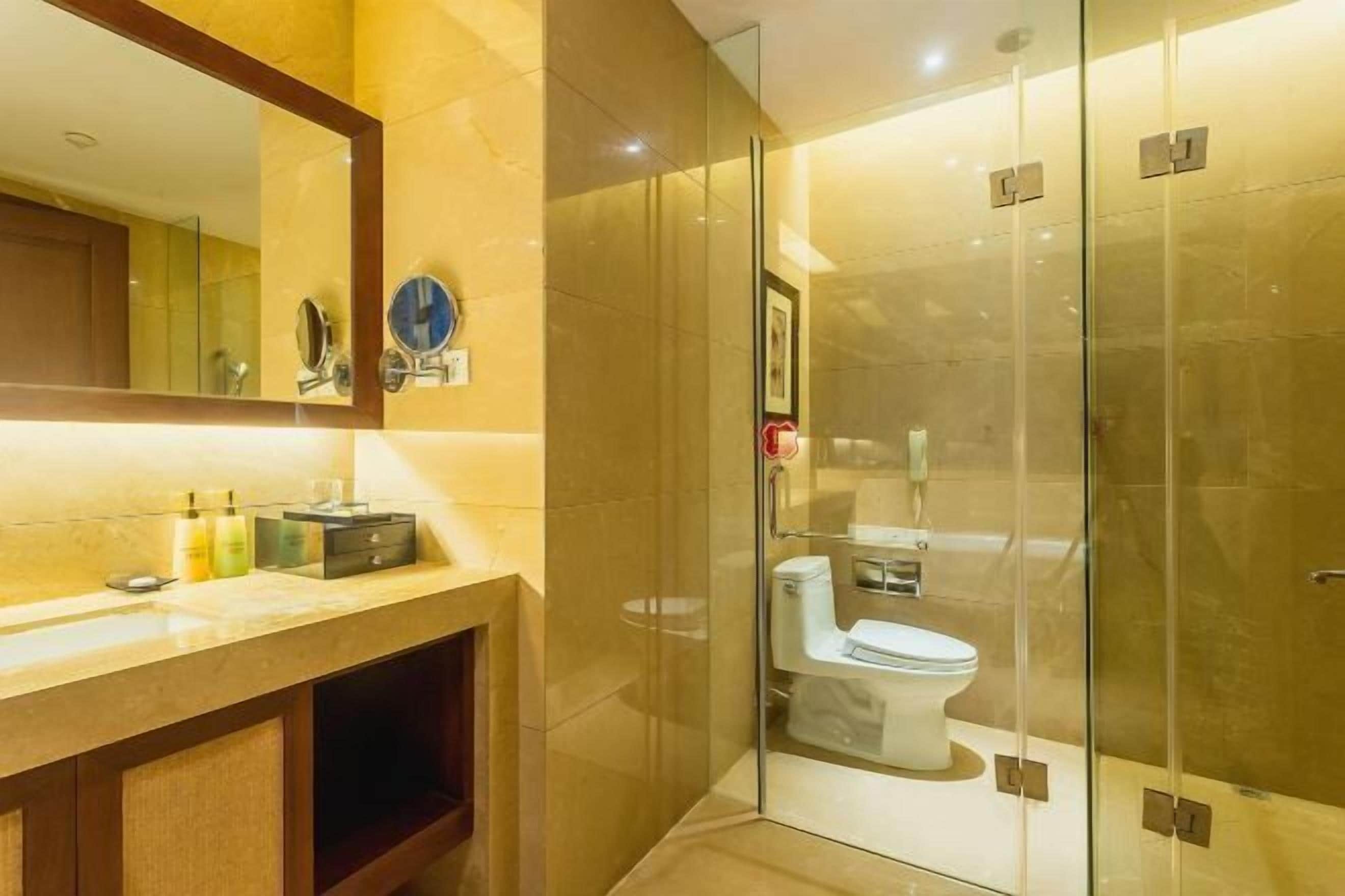 A modern bathroom with a glass shower enclosure, a marble countertop, and a large mirror.