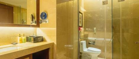 A modern bathroom with a glass shower enclosure, a marble countertop, and a large mirror.