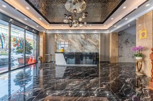 Un vestíbulo moderno con suelo de mármol, un mostrador de recepción y un techo decorativo.